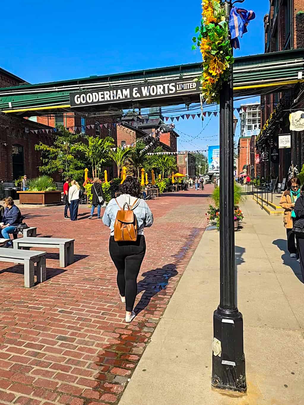 Ashlea walking through the historic Distillery District of Toronto with the Gooderham Worts sign overhead.