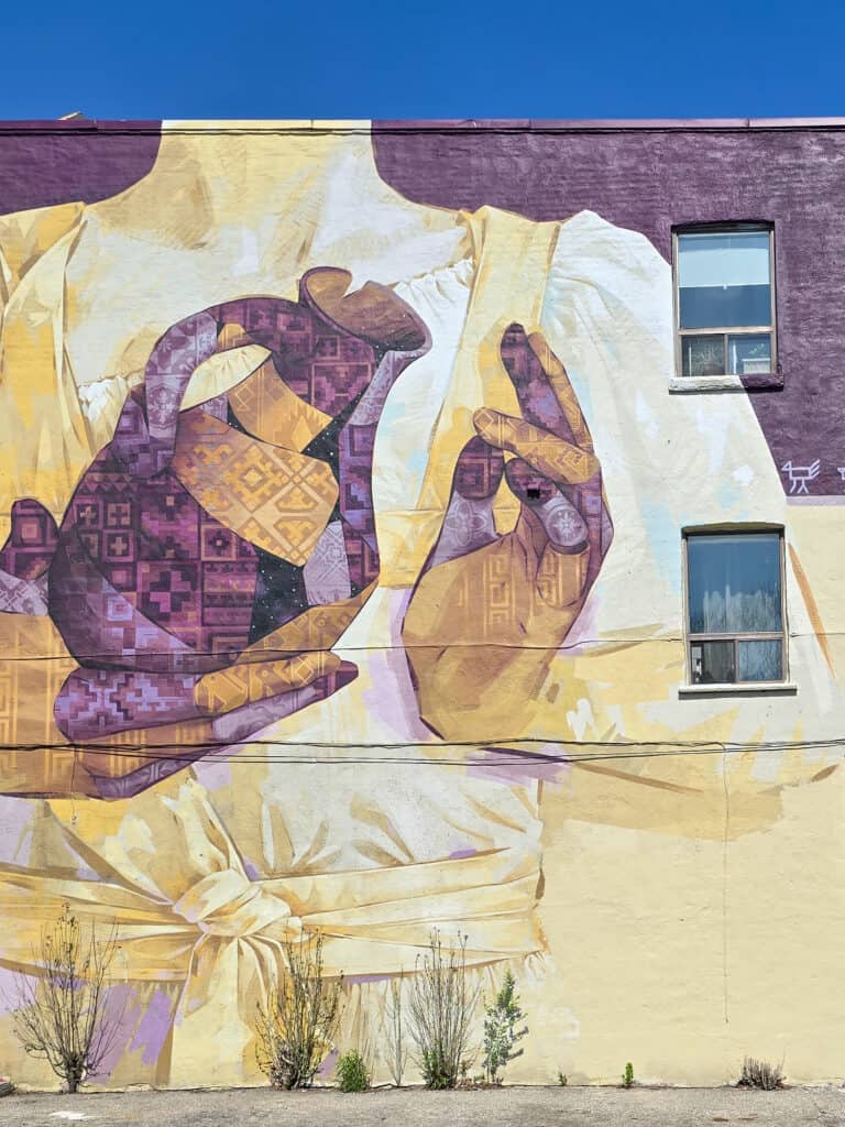 A street art mural of woman holding a pitcher of water in Toronto's Little Portugal.
